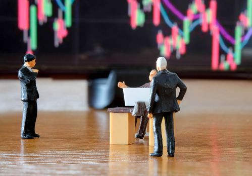 Miniature figure business people or Stock Trader meeting and consulting in front of Blur Price Stock graph board for Graph Analysis