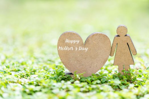 Happy Mother’s Day with heart icon and woman model stand on fresh green grass in garden with copy space for text