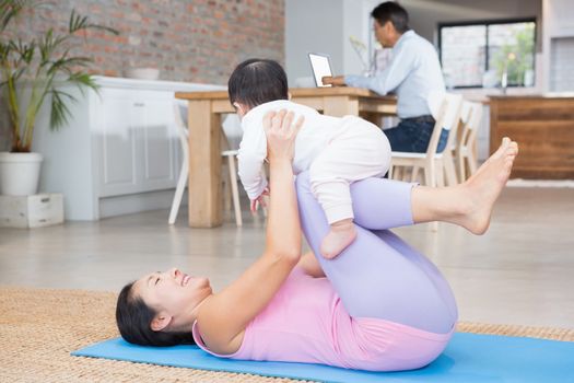 Happy mother and baby daughter exercising on mat at home