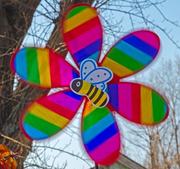 Children's multi-colored toy in the form of a propeller and bee in motion
