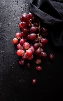 A bunch of red grapes top view on dark background. Dark mood