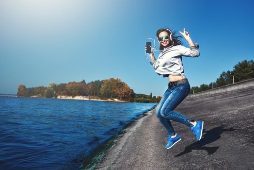 Happy joyful woman listening to music while being outdoor. Music concept.