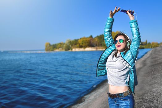 Happy joyful woman listening to music while being outdoor. Music concept.