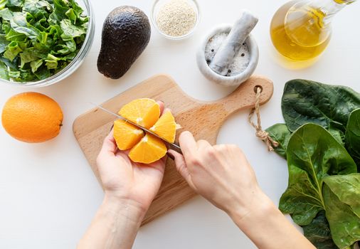 Step by step preparation of spinach, avocado and orange salad. Step 1 - cutting the orange, top view, selective focus