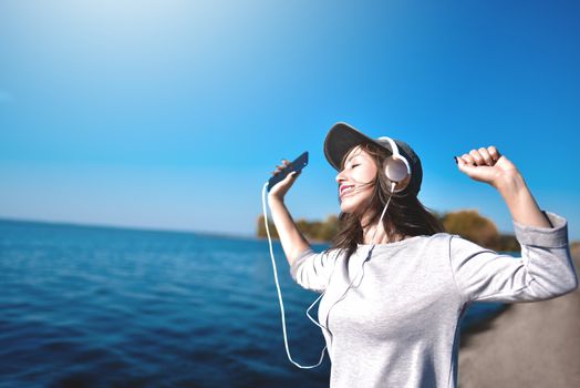 Happy joyful woman listening to music while being outdoor. Music concept.