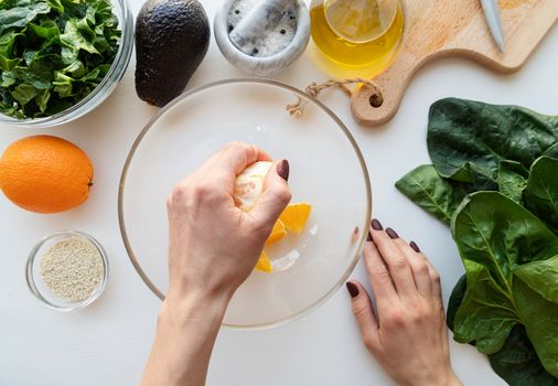 Step by step preparation of spinach, avocado and orange salad. Step 2 - squeezing the orange for the sauce, top view, selective focus