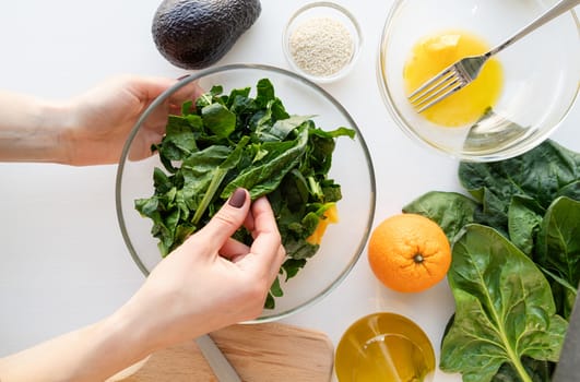 Step by step preparation of spinach, avocado and orange salad. Step 6 - putting together and mixing all ingredients, top view, selective focus