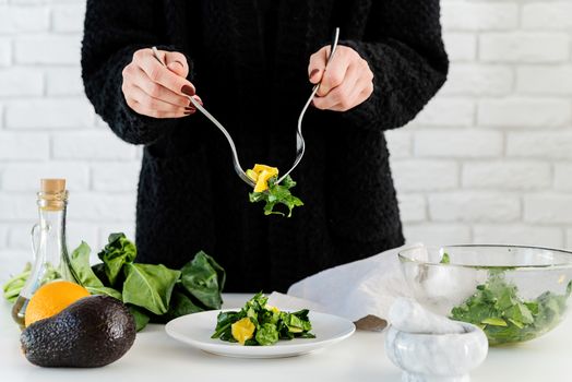 Step by step preparation of spinach, avocado and orange salad. Step 7 - putting the salad to the serving plate, front view, selective focus