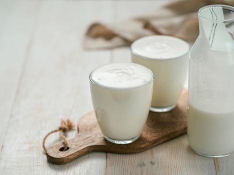 Kefir, buttermilk or yogurt with probiotics. Yogurt in glass on white wooden background. Probiotic cold fermented dairy drink. Gut health, fermented products, healthy gut flora concept. Copy space