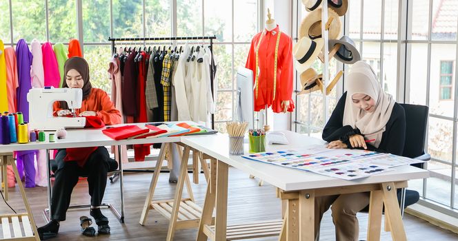 Small business of Muslim woman fashion designer Working and  using smart phone and tablet With Dresses at clothing store