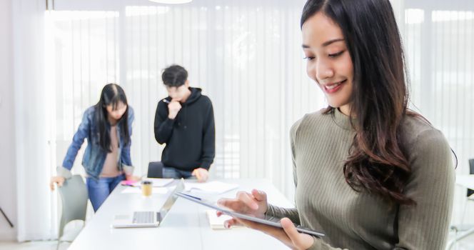 Asian female students use digital tablets to find information for work and study online.