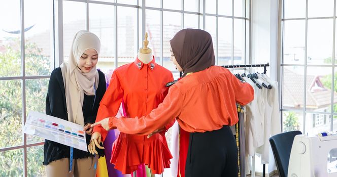 Small business of Muslim woman fashion designer Working and  using smart phone and tablet With Dresses at clothing store