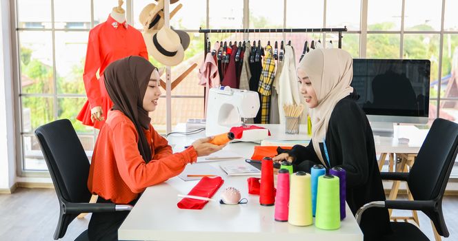 Small business of Muslim woman fashion designer Working and  using smart phone and tablet With Dresses at clothing store