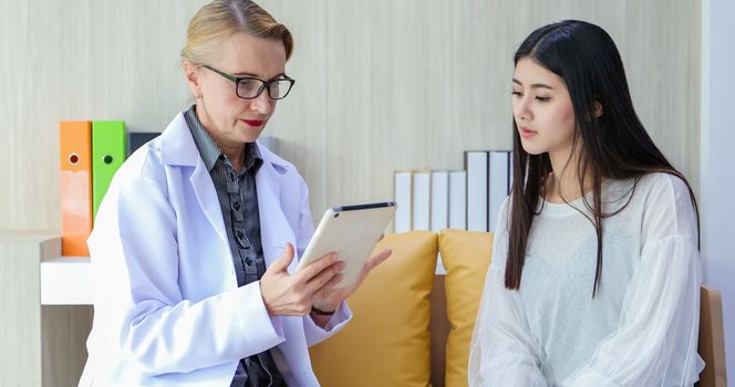 Doctor using digital tablet for explaining medication to woman patient and visit at home