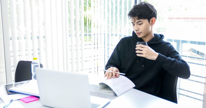 Asian man students read books and use computer notebook to find information for work and online studies.