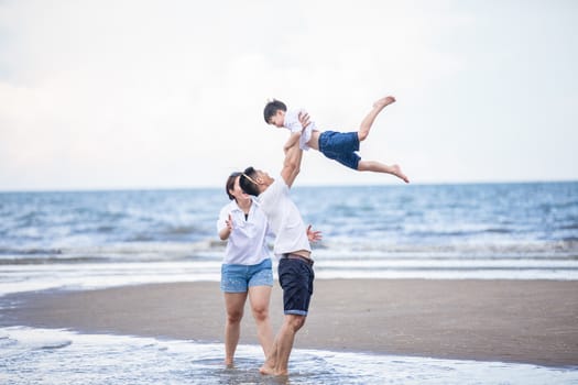 Active parents and people outdoor activity on summer vacations and holiday with children.Happy family and son walk with fun of sunset sea on sand beach.