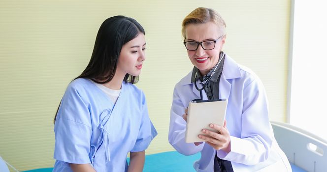 Doctor using digital tablet for explaining medication to woman patient in his office at Hospitals