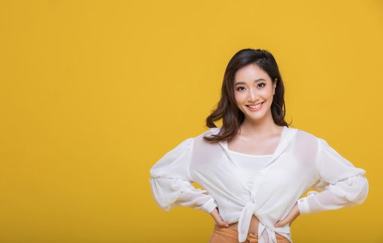 Portrait Asian beautiful happy young woman smiling cheerful and looking at camera isolated on yellow studio background