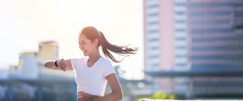 Asian women is watching the sport watch or smart watch for jogging on city