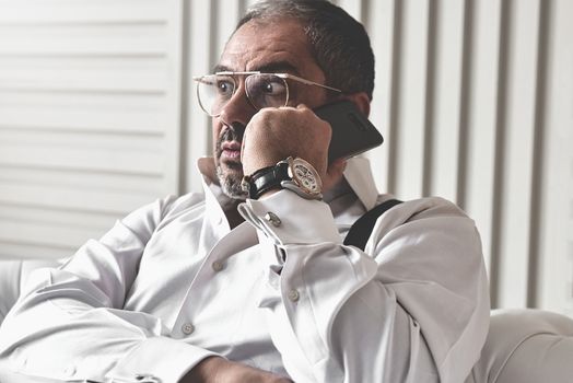 The bad news. Seriously displeased businessman talking on the phone in his office