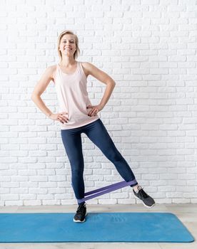 Stay home. Home fitness. Young smiling woman exercising at home using rubber resistance band