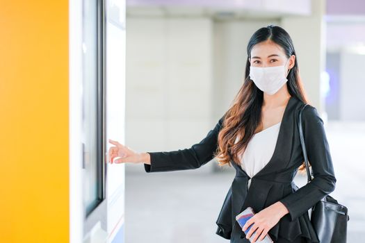 Beautiful business woman with hygiene mask point to sky train or transportation map at the station to select the destination of working during Covid-19 pandemic in city.