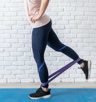 Stay home. Home fitness. A woman exercising legs at home using rubber resistance band