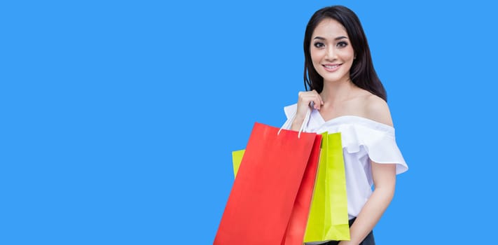Beautiful asian young woman with shopping bags with smile while standing at the clothing store. Happiness, consumerism, sale and people concept
