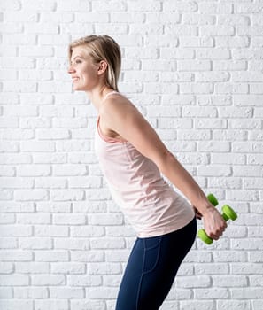 Stay home. Home fitness. Smiling young woman exercising with dumbbells at home