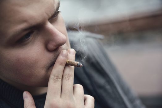 Guy smokes a cigarette outside, portrait, close-up