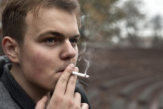 Guy smokes a cigarette outside, portrait, close-up