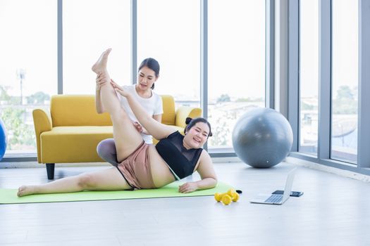 Two Asian woman watching and learning yoga exercising online on computer notebook labtop at home ,concept activity and relax at home 