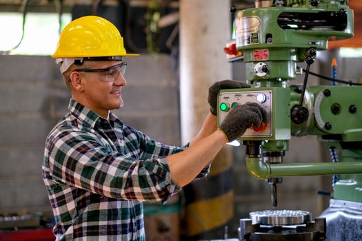 Side view of smart technician or engineer worker with protective uniform work with machine and look happy in factory workplace. Concept of good system of management get better industrial business.