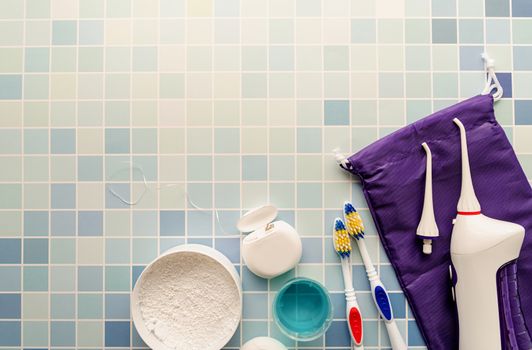 Oral hygiene, dental tools, dental floss, mouth irrigator, toothbrushes and tooth powder top view on blue background