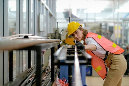 Factory technician or worker woman with safety uniform hold copper tube and look to camera in manufacture workplace. Concept of good management for industrial business with professional employee.