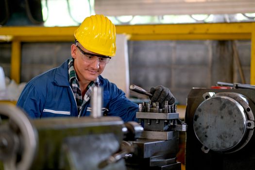 Front view of smart technician or engineer worker with protective uniform work with machine and look happy in factory workplace. Concept of good system of management get better industrial business.