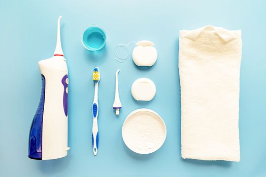 Oral hygiene, dental tools, dental floss, mouth irrigator, toothbrushes and tooth powder top view on blue background