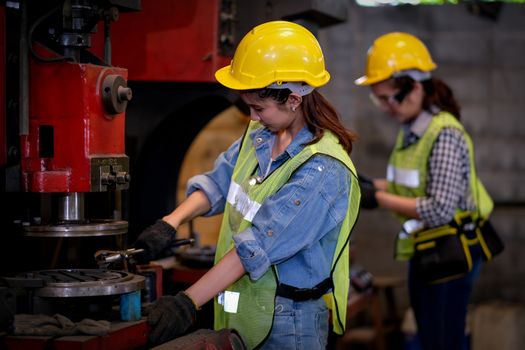 Pretty woman workers or technician are working with machine in factory.