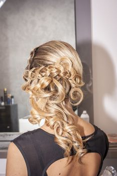 Girl at the hairdresser is styled and made up for the occasion