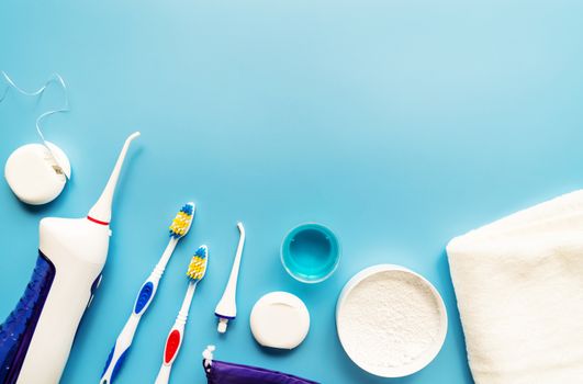 Oral hygiene, dental tools, dental floss, mouth irrigator, toothbrushes and tooth powder top view on blue background. Copy space