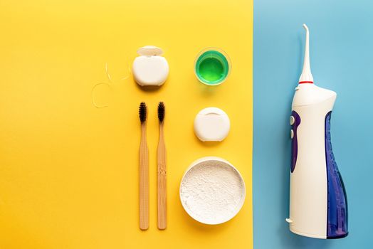 Oral hygiene, dental tools, dental floss, mouth irrigator, toothbrushes and tooth powder top view on blue background. Copy space