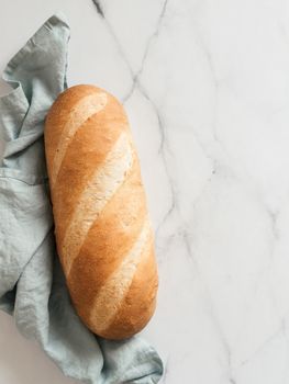 British White Bloomer or European Baton loaf bread on white marble background. Top view or flat lay. Copy space for text or design. Vertical.