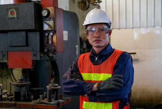 Asian worker or technician man stand with confident action in front of the machine in factory. Concept of good system and manager support for better industrial business.