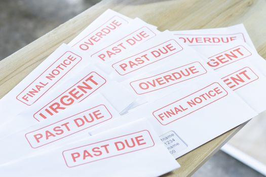 Debt letters that are collected on past overdue bills and final announcements on the table. Red writing to represent the struggle against economic unemployment.