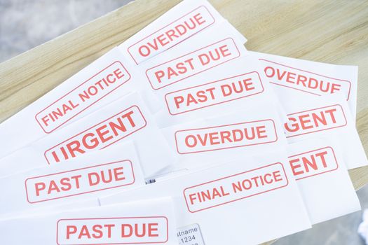 Debt letters that are collected on past overdue bills and final announcements on the table. Red writing to represent the struggle against economic unemployment.



J