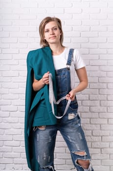 Portrait of a young caucasian woman tailor holding the textile and a tape measurer