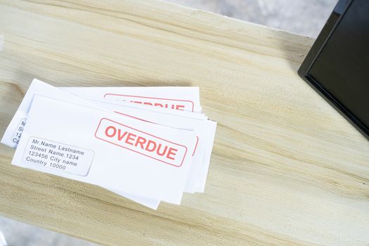 Debt letters that are collected on past overdue bills and final announcements on the table. Red writing to represent the struggle against economic unemployment.
