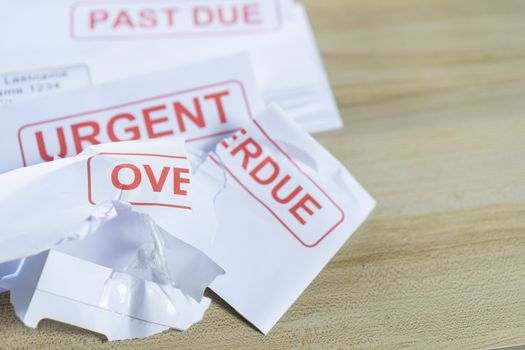 Debt letters that are collected on past overdue bills and final announcements on the table. Red writing to represent the struggle against economic unemployment.