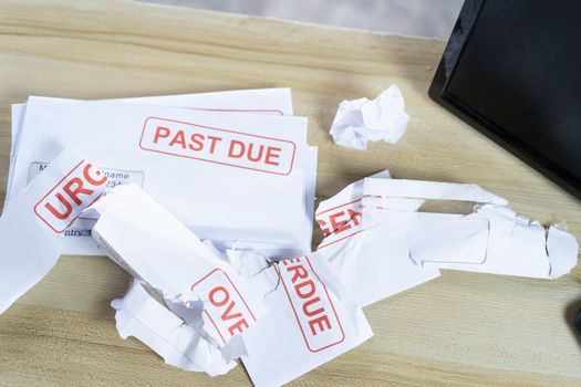 Debt letters that are collected on past overdue bills and final announcements on the table. Red writing to represent the struggle against economic unemployment.