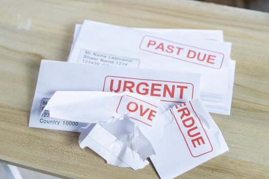 Debt letters that are collected on past overdue bills and final announcements on the table. Red writing to represent the struggle against economic unemployment.